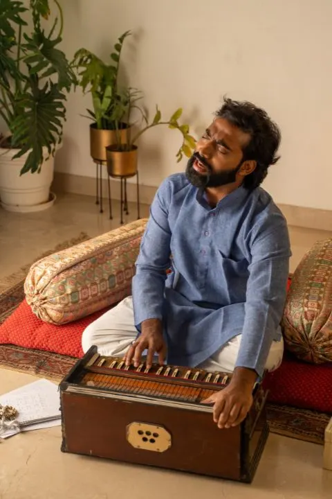 Man singing devotional keerthanas while playing a harmonium near palace hostel, Mysore