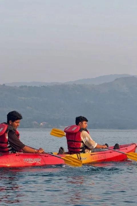 Two people kayaking on calm backwaters surrounded by hills and nature